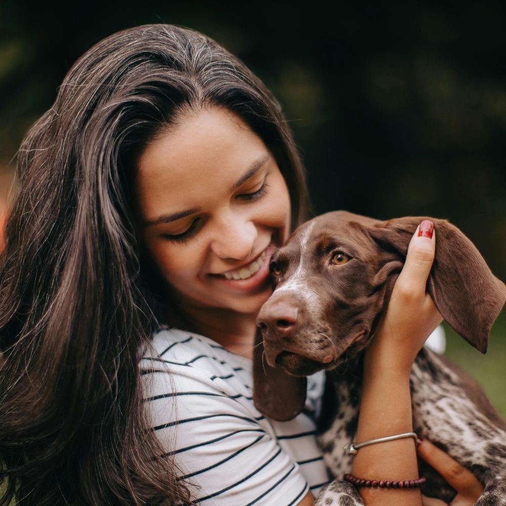 A person is holding their dog in the grass